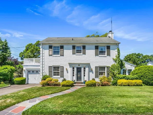 A well-kept white colonial home with a manicured lawn